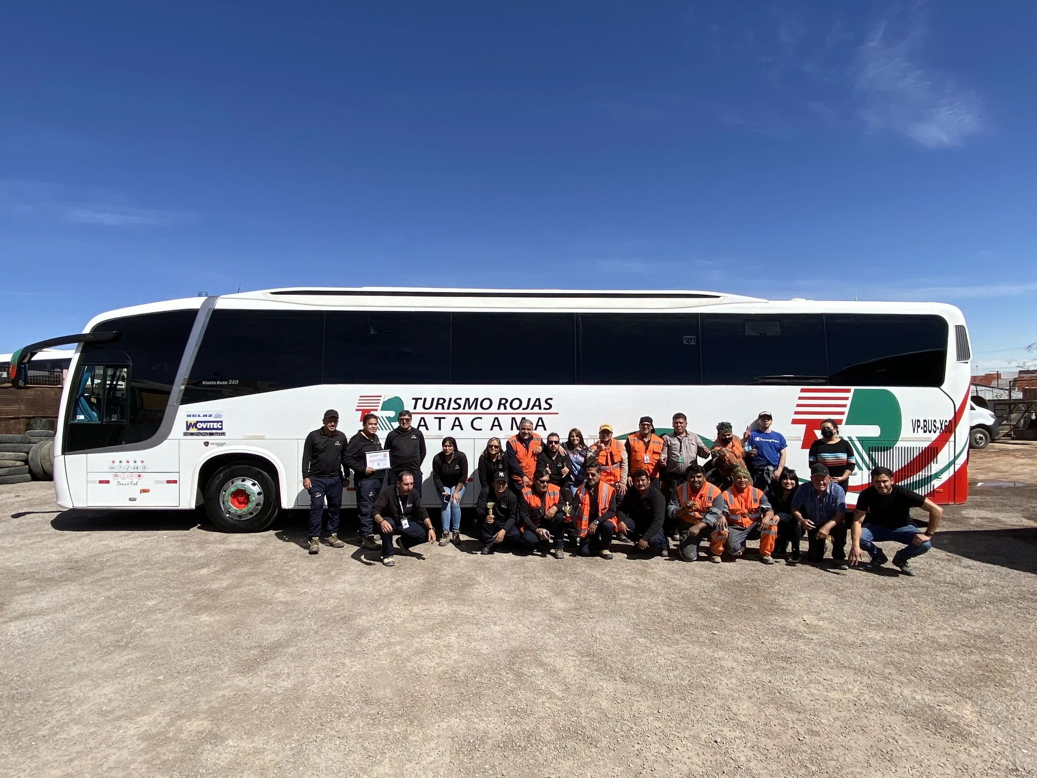 Colaboradores TRA ordenados junto a un bus de la empresa